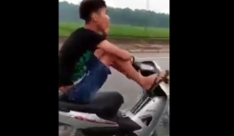 Thanh niên lái xe máy bằng chân, tay cầm điện thoại gọi nói chuyện với mẹ